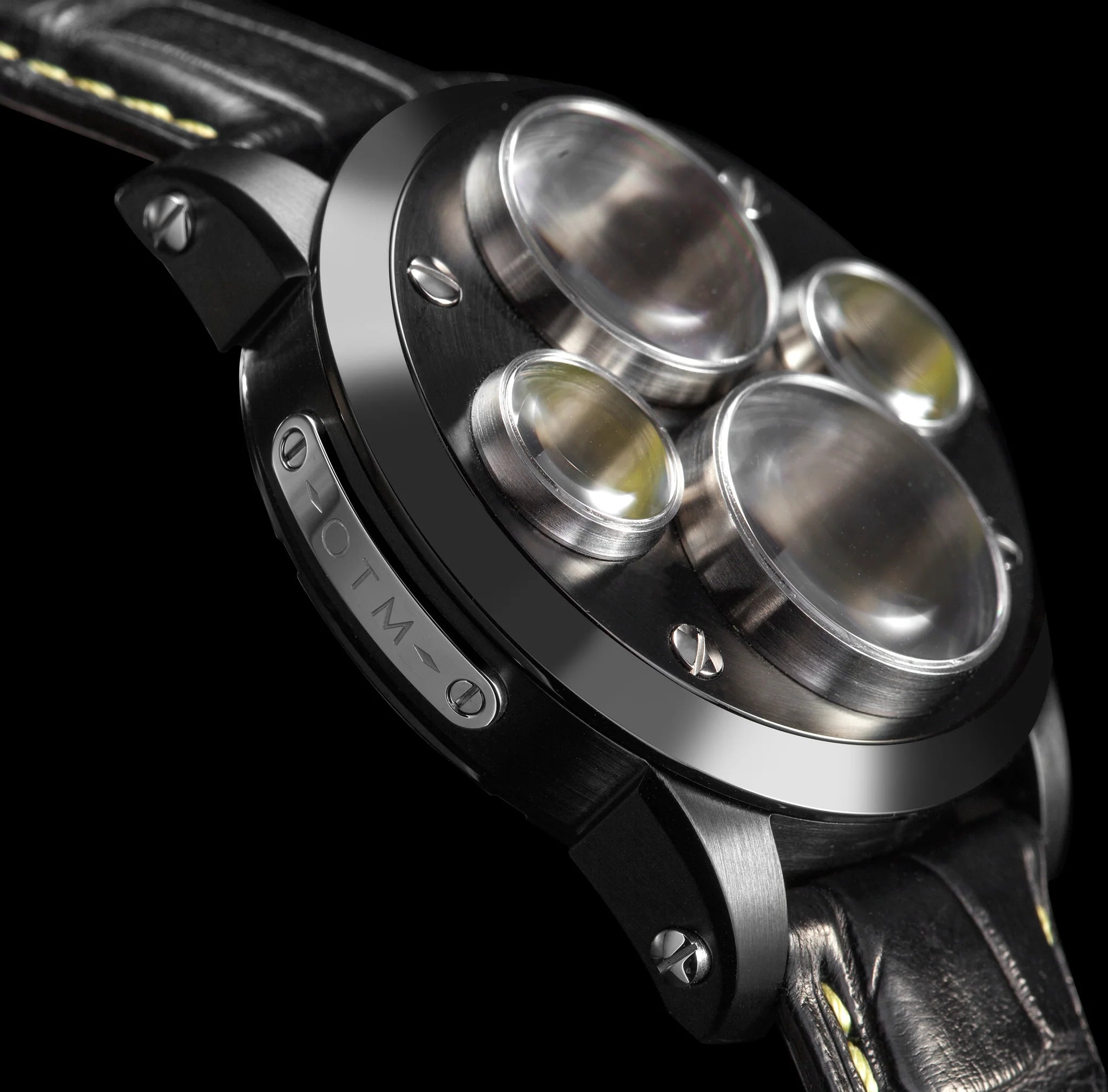 Close-up of a watch with a metallic case and leather strap on a black background