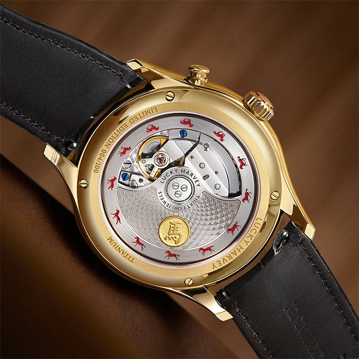Gold watch with black leather strap on a brown background