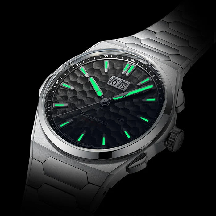 A silver stainless steel wristwatch with a textured black dial and bright green luminescent hands, indices, and date daymark, shown against a solid black background.