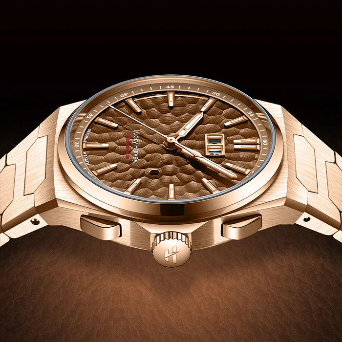 A luxury men's watch with a brushed rose gold-tone metal case and integrated bracelet, featuring a textured brown dial with a date window and a small red brand accent.