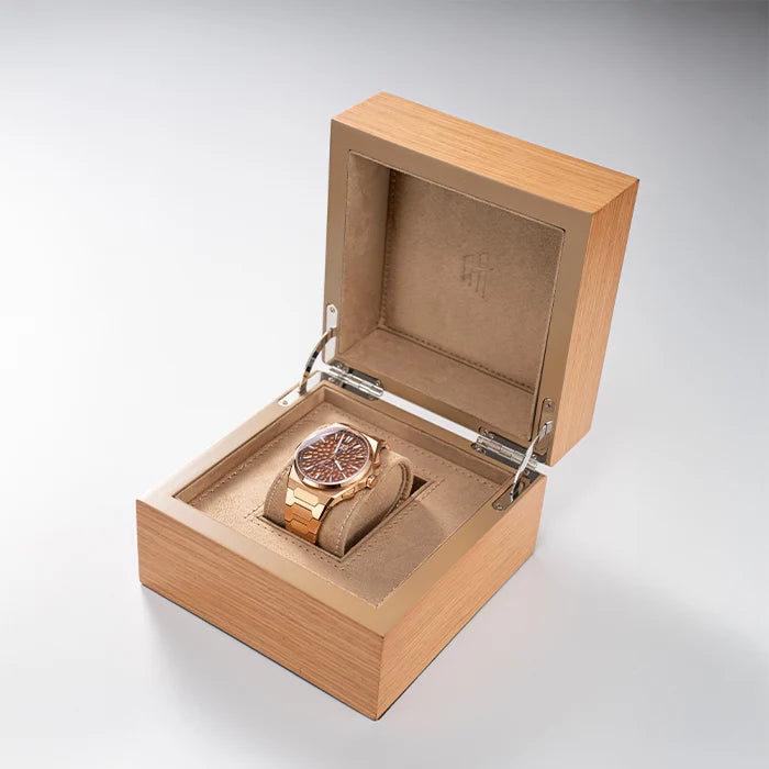 Wooden watch box with a rose gold watch inside on a light gray background