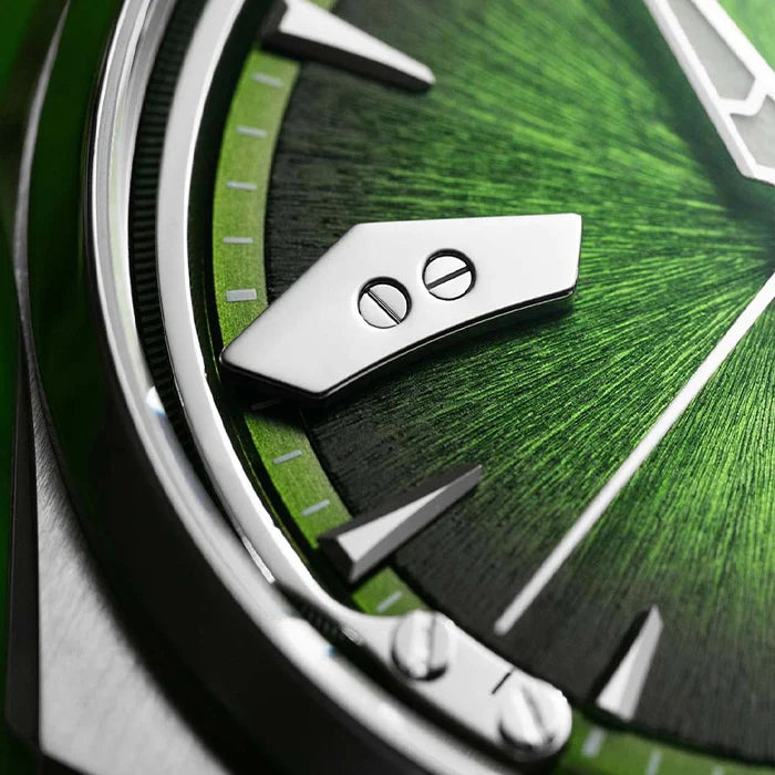 Extreme close-up of a luxury watch dial featuring a vibrant green sunburst textured finish, polished silver-tone screw-shaped hour markers, and a polished bezel.