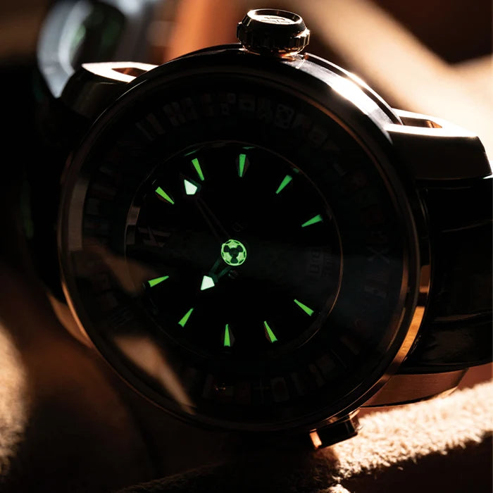 Close-up of a watch with a glowing green face on a dark background