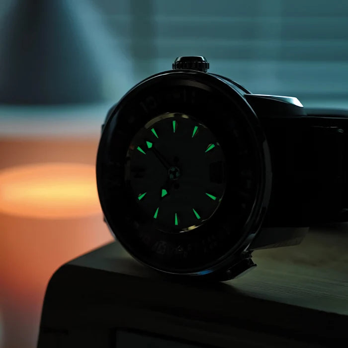 Black wristwatch with glowing green face on a blurred background