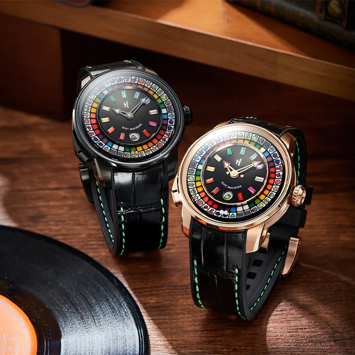 Two ornate watches with colorful face designs on a wooden surface.