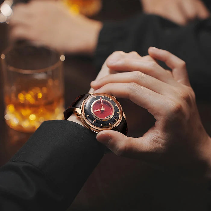 Person holding a watch with a glass of whiskey in the background