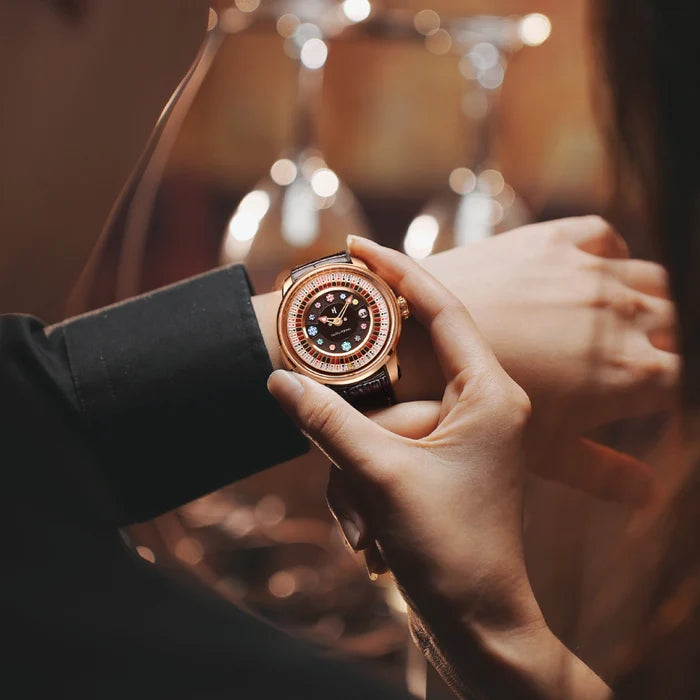 Person adjusting a rose gold watch with a dark face on a blurred background