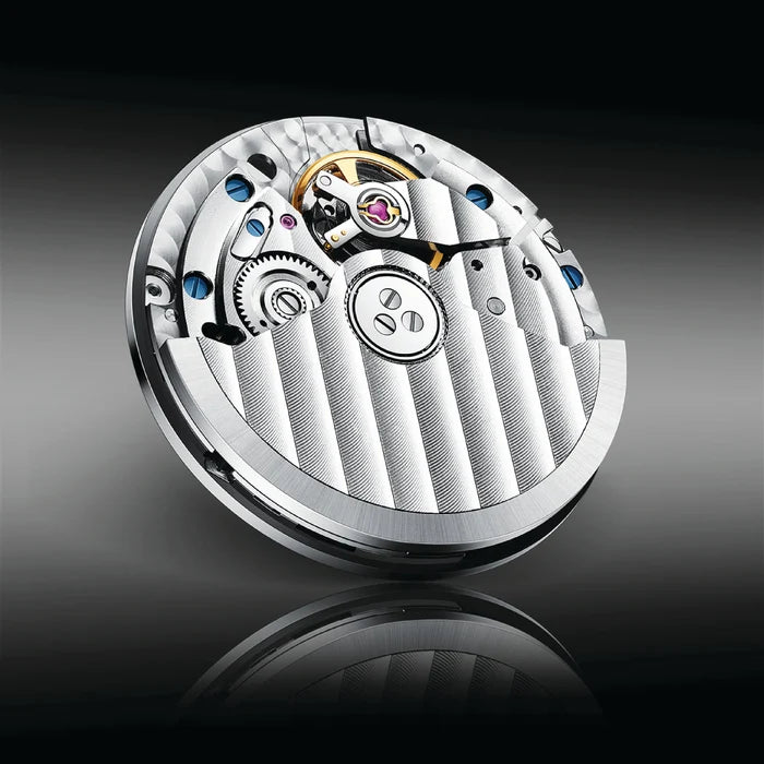 Close-up of a mechanical watch movement on a reflective surface with a dark background