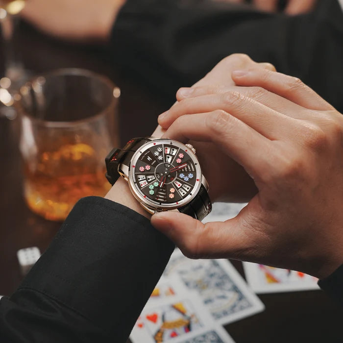 Person adjusting a watch with a glass of whiskey and playing cards in the background