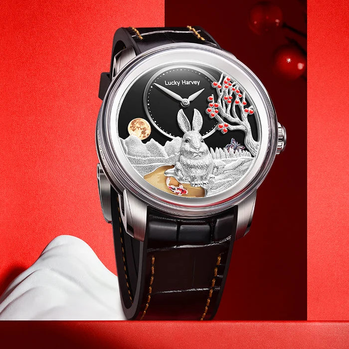 A luxury watch by Lucky Harvey, featuring a detailed rabbit and moon watch face with silver-toned elements, a black dial, and a black leather strap, set against a red background with a white hand partially visible.