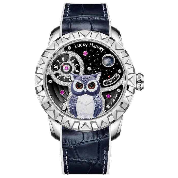 A luxury mechanical watch by Lucky Harvey, featuring a silver-toned bezel, a dark blue alligator leather strap, and a detailed dial with an owl illustration, stars, and pink accents.