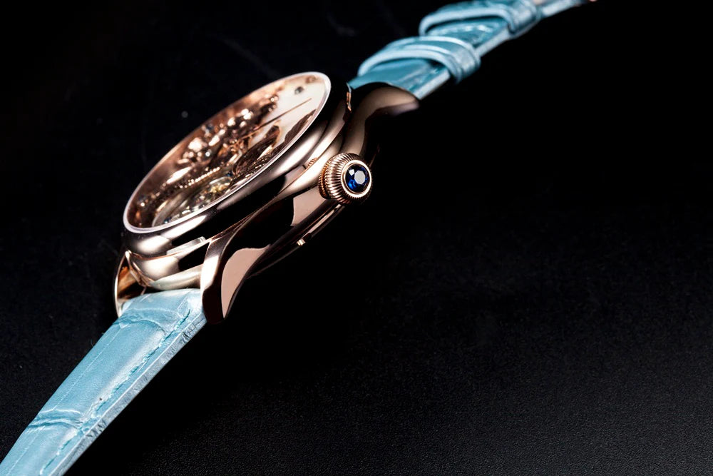 Luxury watch with blue strap and rose gold case on a black background
