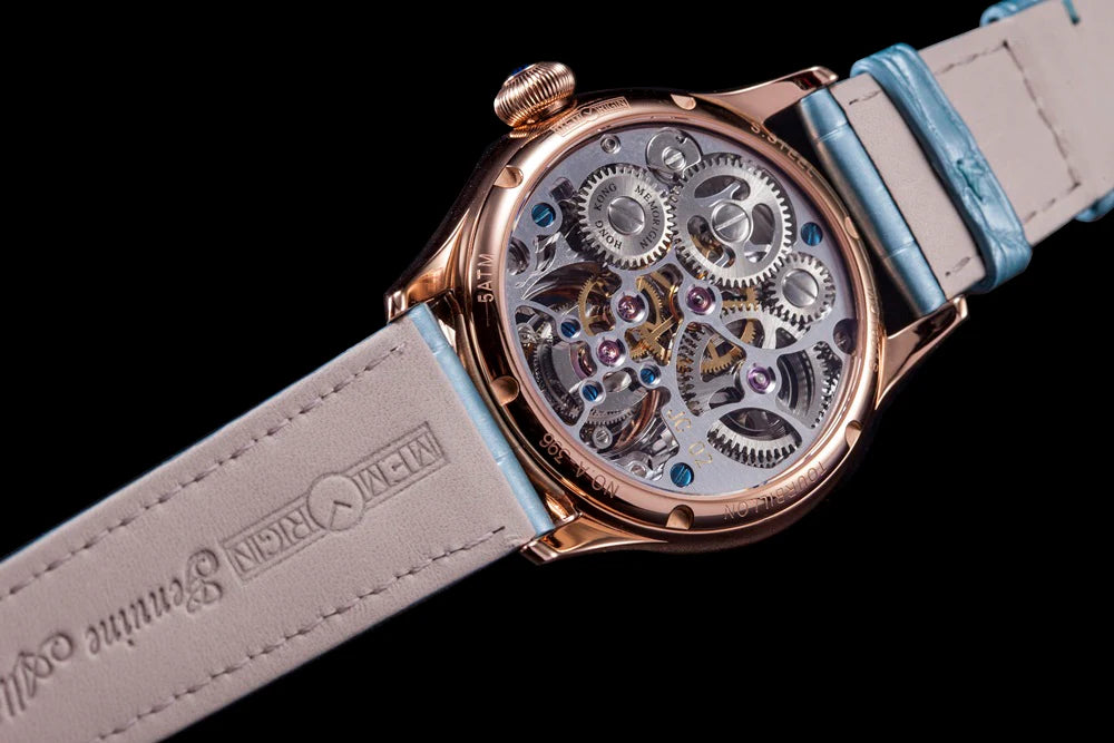 Watch with visible mechanical components and a light blue strap on a black background