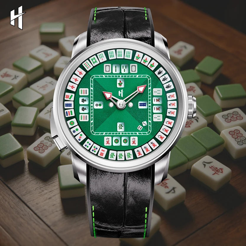 A wristwatch with a green mahjong-themed dial and black leather strap, styled on a wooden surface surrounded by mahjong tiles. The watch has a silver-toned case and a white logo on the upper left.