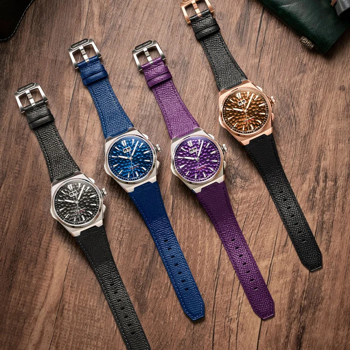 Four watches with different colored straps on a wooden surface