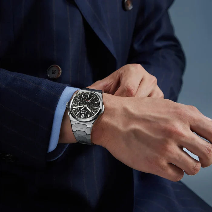 Person wearing a silver watch on a blue background