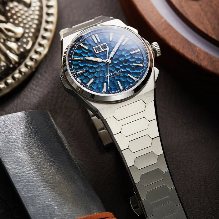 Luxury watch with blue textured dial and silver metal band on a dark surface