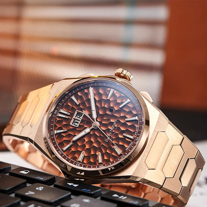 Luxury rose gold watch with a textured brown dial on a blurred keyboard background