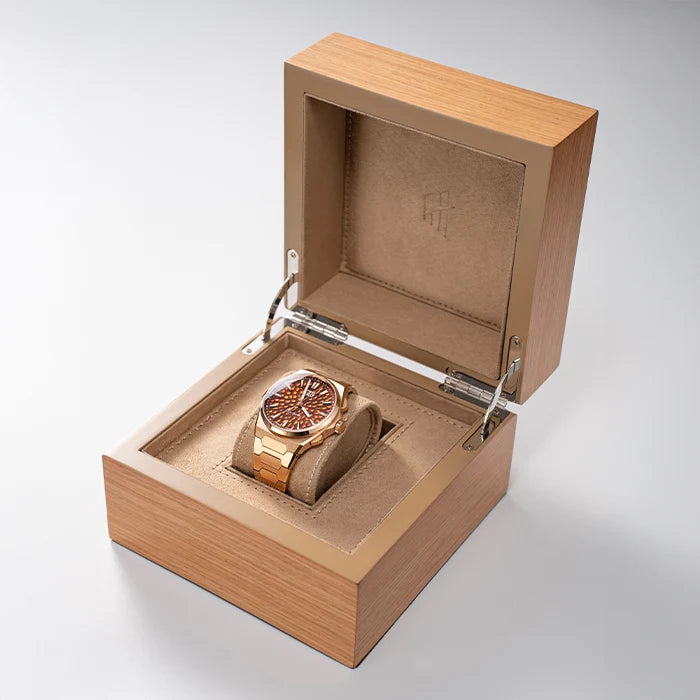 Gold watch in a wooden box on a light gray background
