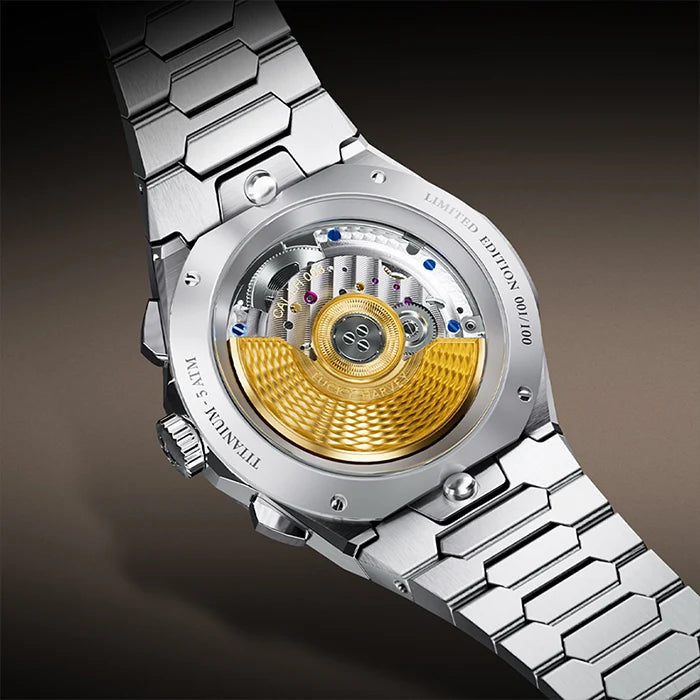 Close-up of the back of a titanium watch with a visible mechanical movement, featuring a silver stainless steel link bracelet and a prominent gold-toned rotor.