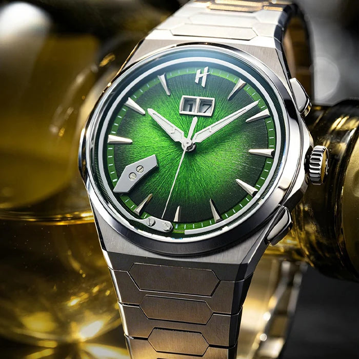 A close-up of a titanium wristwatch with a bright green sunburst dial, silver-tone case, and matching metal link bracelet, set against a blurred golden background.