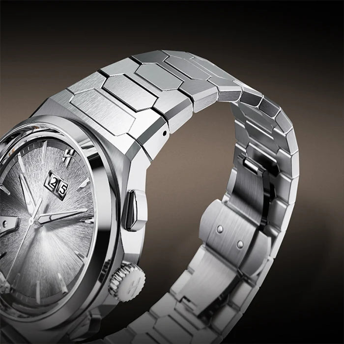 A close-up studio shot of a silver titaniuml wristwatch with a textured dial and a matching segmented metal link bracelet, set against a dark gradient background.