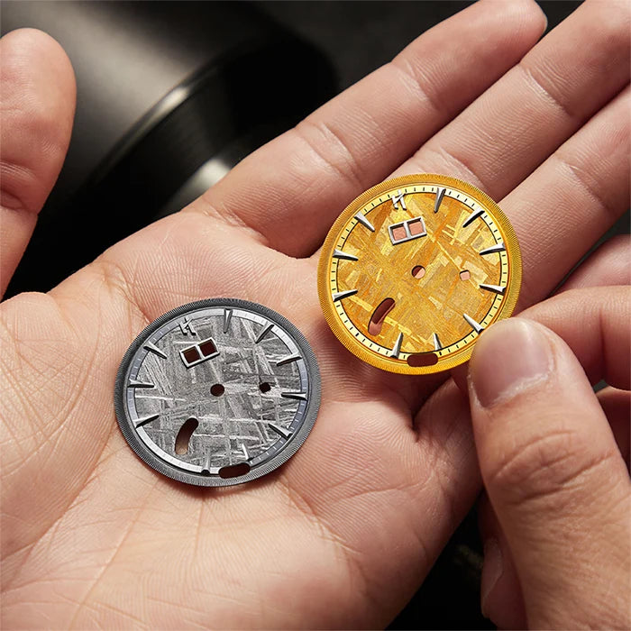 Two coins, one gold and one silver, held in a hand against a blurred background.
