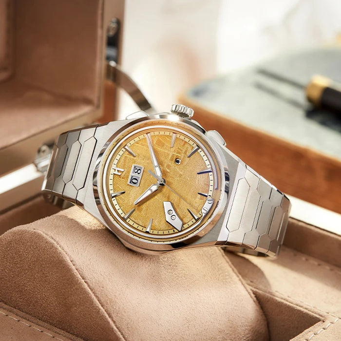 Luxury watch with gold face and silver metal band on a brown cushion
