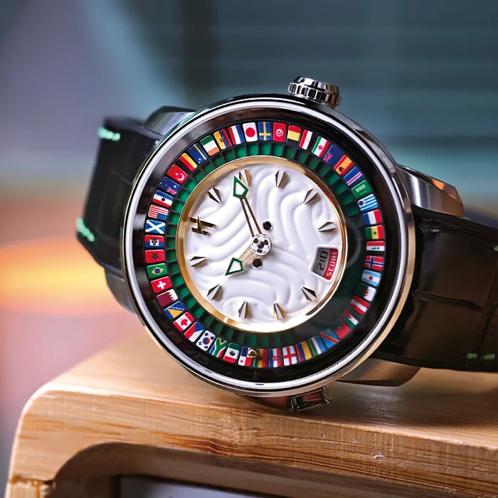 A luxury watch with a black leather strap, a silver-toned case, and a white wavy dial. The bezel is decorated with numerous colorful national flags, and the hands are green and gold.